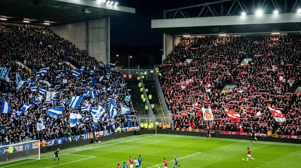 Estadio de futbol ingles con aficiones rivales separadas durante un derbi de la Premier League